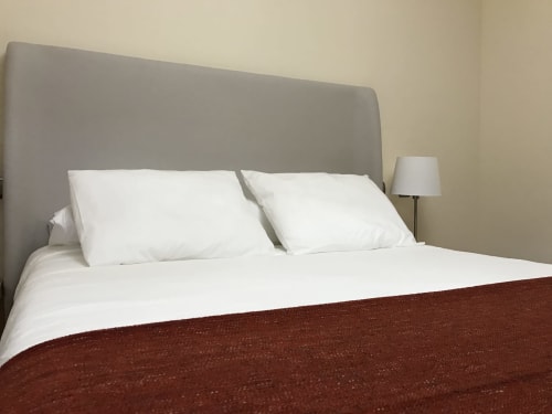 Bedroom at A Quinta de Lapido cottage with gray headboard, white pillows, burgundy bedspread, and bedside lamp