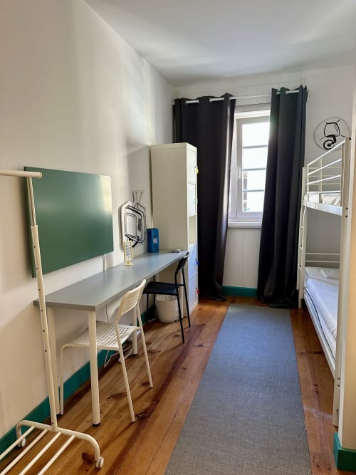 Meu quarto em dormitório misto no albergue de Guimarães com beliches, escrivaninha, quadro verde e janela