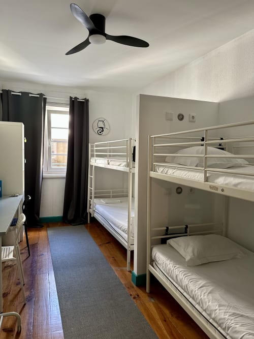 Quarto familiar moderno em My Hostel em Guimarães com beliches brancos, piso de madeira e banheiro compartilhado