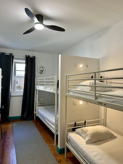 Quarto de dormitório moderno em My Hostel Guimarães com camas beliche, ventilador de teto e banheiro compartilhado