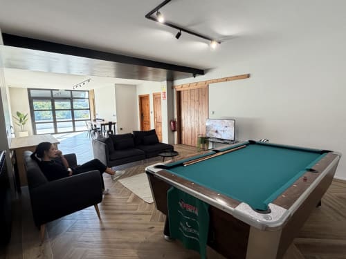 Modern cottage game room with pool table, black seating, and wooden accents at A Quinta de Lapido, Spain