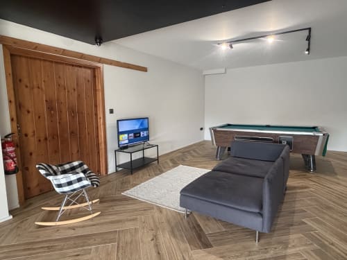 Modern cottage recreation room at A Quinta de Lapido BnB in Spain featuring pool table, TV, rocking chair and lounge seating.
