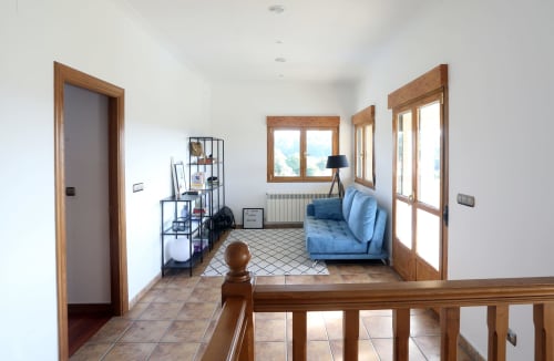 Bright cottage living area at A Quinta de Lapido with blue sofa, wooden doors, windows, and tile flooring