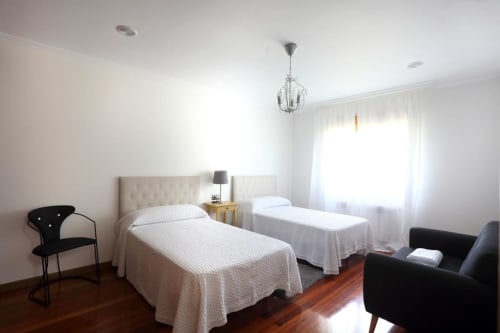 Luminoso dormitorio doble en A Quinta de Lapido con ropa de cama blanca, lámpara colgante, suelo de madera y mobiliario moderno