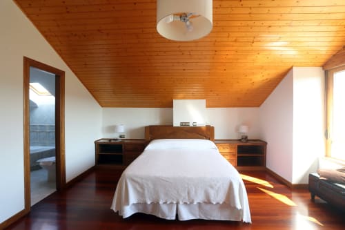 Luminoso dormitorio en ático con techo de madera en Quinta de Lápido, España. Cama doble con sábanas blancas, muebles de madera y
