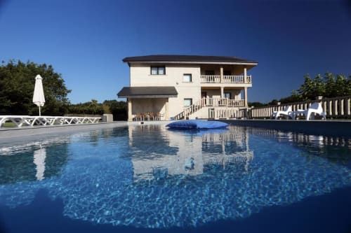 La Quinta de Lapido, un bed & breakfast en España, cuenta con una lujosa piscina de agua azul que refleja la elegante casa de tres pisos color crema