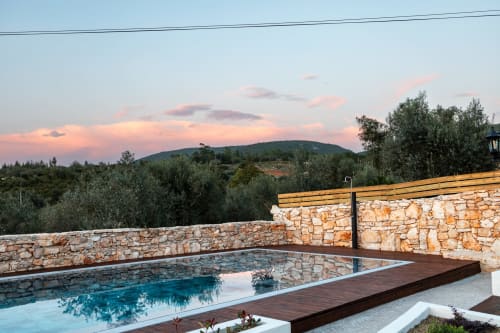 Vista do pôr do sol da piscina Recantos D'Almerinda com muros de pedra e oliveiras em Pombal, Portugal