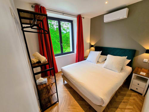Modern bedroom at Vindihouses Épinac with queen bed, green headboard, red curtains, loft ladder, and garden view