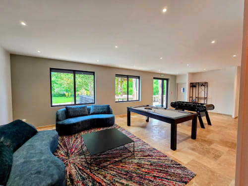 Modern games room at Vindihouses cottage in Épinac with blue velvet seating, pool table, foosball, colorful rug, and garden
