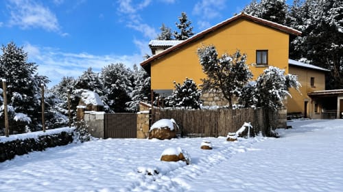 Casa alpina amarilla en ALTOGREDOS en Hoyos del Espino nevado, con árboles escarchados y cerca de piedra