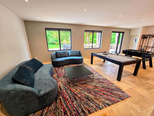 Modern recreation room at Vindihouses cottage in Épinac with pool table, foosball, curved sofas, and garden views