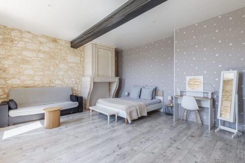 Spacious bedroom at Domaine De Pimpine with stone walls, star-patterned wallpaper, bed, sofa, and modern amenities in Galgon