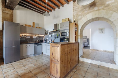 Modern kitchen with wooden island and exposed beams at Domaine De Pimpine, Galgon