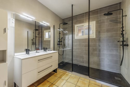 Modern bathroom at Domaine De Pimpine with double vanity, rainfall shower, black fixtures, and heated towel rack