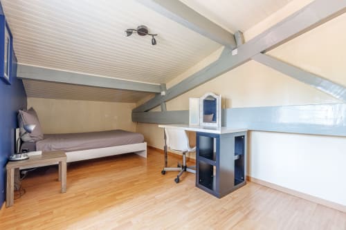 Modern attic bedroom with wooden floor, bed, desk, and sloped ceiling at Domaine De Pimpine, Galgon