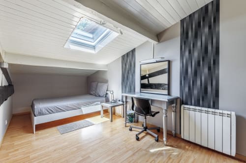 Modern attic bedroom at Domaine De Pimpine with skylight, desk, TV, and wood flooring in Galgon
