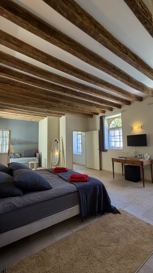 Spacious lake-view bedroom at Cloffy B&B with exposed wooden beams, king bed, desk, and lounge area