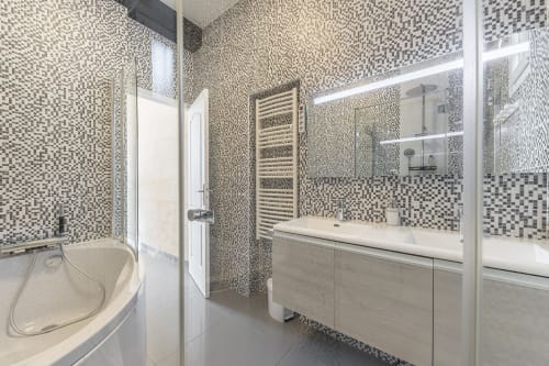 Modern bathroom at Domaine De Pimpine cottage with mosaic tile walls, white vanity, shower, and heated towel rack