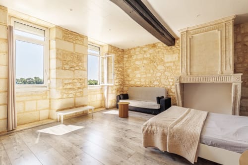 Spacious bedroom at Domaine De Pimpine cottage with stone walls, river views, fireplace, and modern amenities