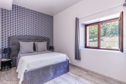 Modern bedroom at Domaine De Pimpine cottage in Galgon with patterned accent wall, gray upholstered bed, and river view