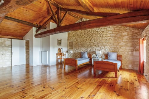 Stone cottage bedroom with wooden beams, two beds, and exposed stone walls at Domaine De Pimpine, Galgon