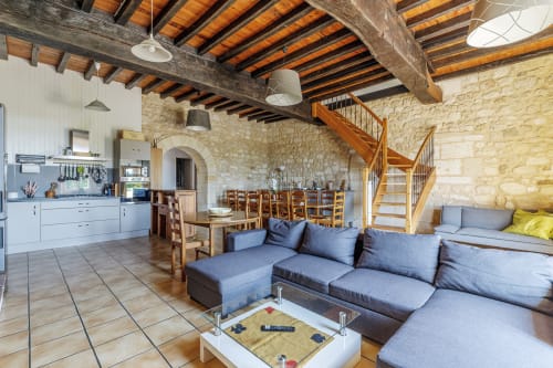 Stone cottage interior with blue sofa, dining area, kitchen, and wooden beam ceiling at Domaine De Pimpine, Galgon