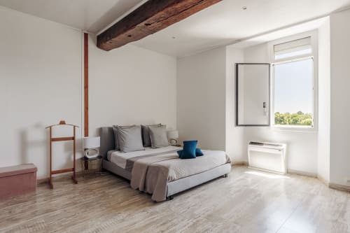 Bright bedroom at Domaine De Pimpine cottage with bed, wooden beams, windows overlooking river, modern amenities