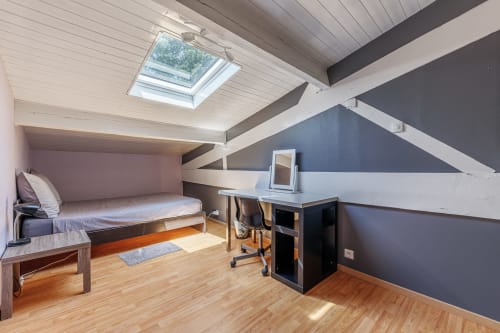Attic bedroom at Domaine De Pimpine with skylight, wooden desk, bed, and blue accent walls in Galgon cottage