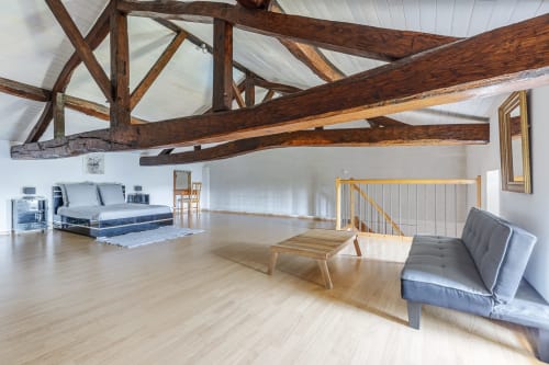 Spacious loft bedroom at Domaine De Pimpine with exposed wooden beams, hardwood floors, modern furnishings and river views