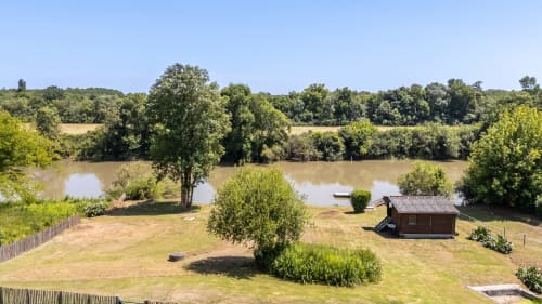 Brick cottage by the Dordogne River at Domaine De Pimpine, surrounded by green grounds and trees, Galgon France