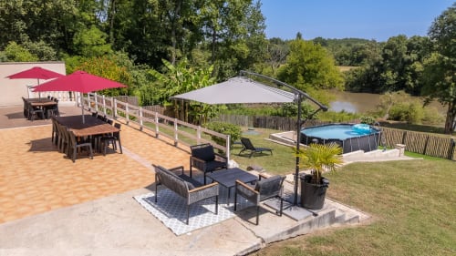 Riverside cottage terrace at Domaine De Pimpine with dining area, lounge seating, pool, and river view in Galgon, France