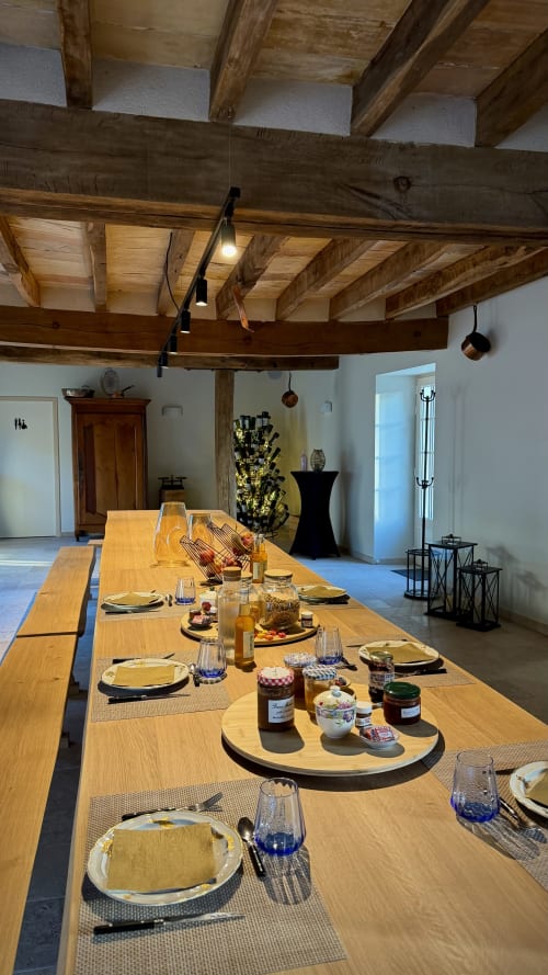 Elegant dining setup in Cloffy reception hall with wooden beamed ceiling, long table settings, and rustic French country