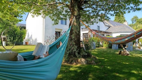 Deux hamacs suspendus aux arbres dans le jardin verdoyant de Ty Coz Breizh, maison d’hôtes à Guidel en Bretagne Sud, pour un moment de détente et de lecture.