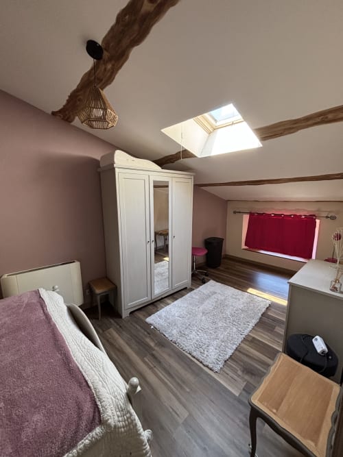 Chambre mansardée charme au Mas Provençal avec poutres apparentes, lucarne, armoire blanche et murs mauve à Bollène