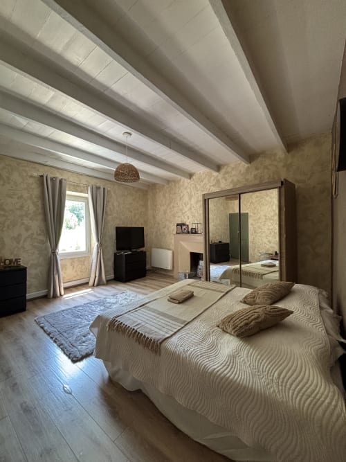 Chambre spacieuse au Mas Provençal à Bollène avec poutres apparentes, armoire miroir et décoration neutre