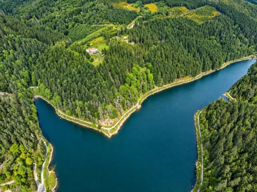 Vue aérienne du gîte Furanelle entouré de forêt dense, au bord d'un lac alpin turquoise à Saint-Étienne, France