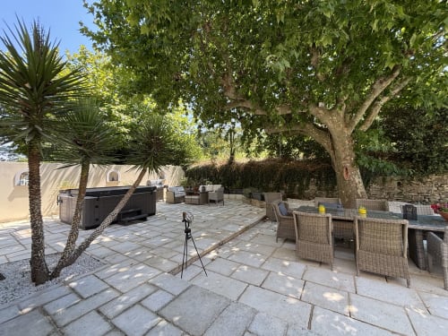Outdoor patio at Mas Provençal in Bollène with seating, hot tub, palm trees and stone terrace under shade