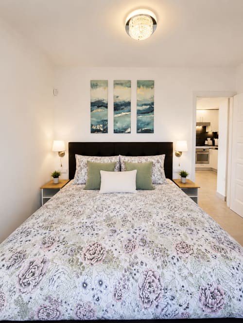 Luxury penthouse bedroom in Playa de las Américas with floral bedding, sea view artwork, and modern amenities