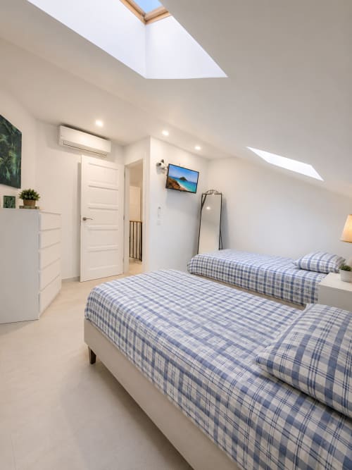 Bright penthouse bedroom at Manage Home Tenerife with twin beds, skylight, and sea view TV