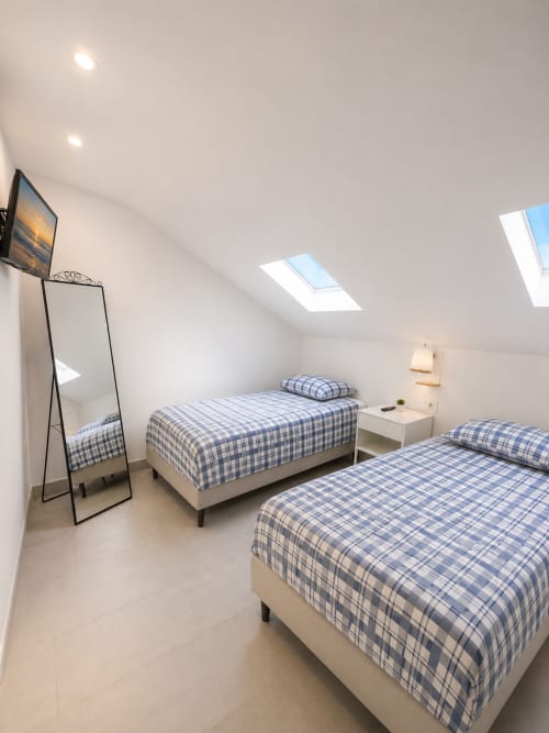 Bright attic bedroom at Manage Home Tenerife with two beds, skylight windows, and modern furnishings in Playa de las Américas