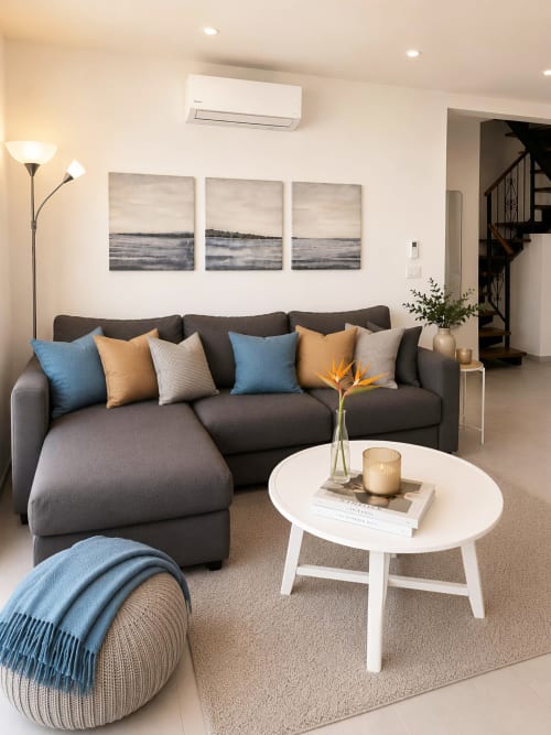 Modern luxury penthouse living room in Playa de las Américas with gray sectional sofa, ocean view artwork, and coastal design