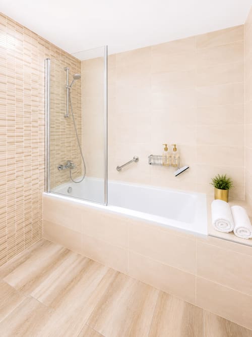 Modern bathroom with walk-in shower, white bathtub, and cream tile walls at Manage Home Tenerife luxury penthouse