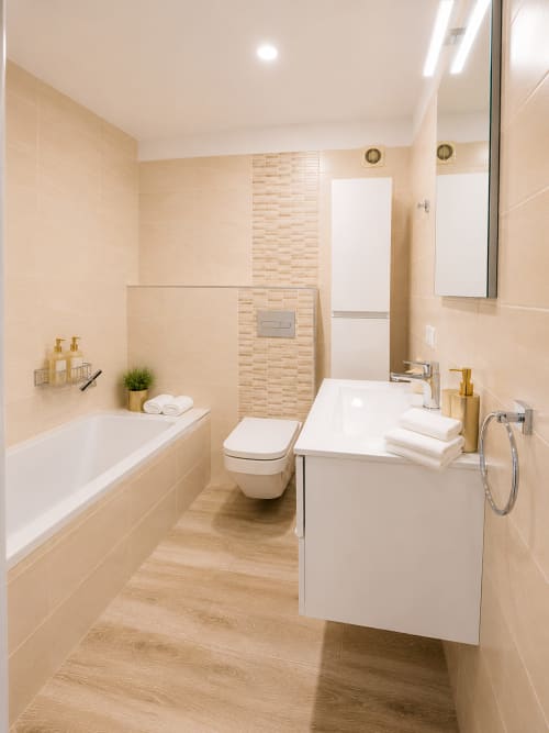 Modern luxury bathroom in Playa de las Américas penthouse with beige tiles, white fixtures, and wood-look flooring