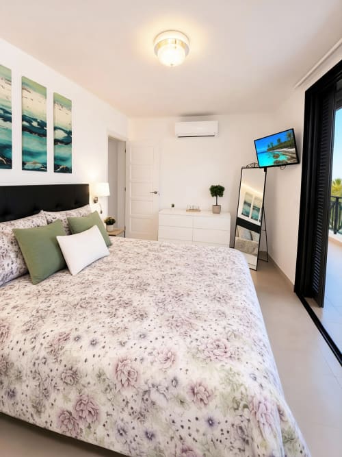 Luxury penthouse bedroom in Playa de las Américas with sea view, modern furnishings, TV, and coastal artwork