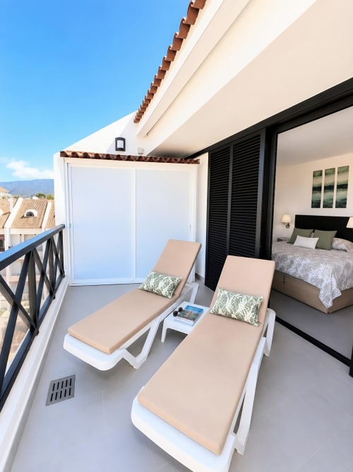Luxury penthouse balcony in Playa de las Américas with lounge chairs, sea view, and bedroom access