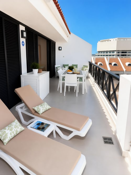 Luxury penthouse balcony in Playa de las Américas with loungers, dining area, and sea views overlooking Tenerife