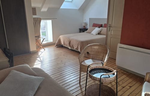 Chambre spacieuse au Domaine de la Cour VAUTIER avec lit, fauteuils en rotin, puits de lumière et vue sur le jardin à Mandeville-en-Bessin