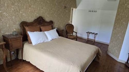 Chambre élégante au Domaine de la Cour VAUTIER avec lit en bois ouvragé, oreillers blancs, literie beige et mobilier ancien