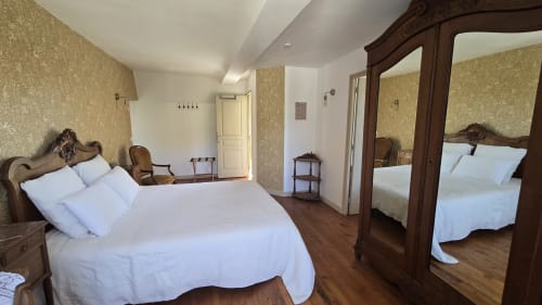Chambre élégante au Domaine de la Cour VAUTIER avec lit en bois ouvragé, linge blanc, mobilier ancien et miroirs