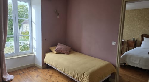 Lit simple avec literie jaune dans chambre mauve au Domaine de la Cour VAUTIER, Mandeville-en-Bessin, vue sur jardin